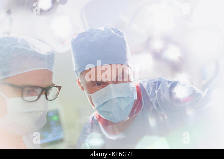 Surgeons wearing surgical mask looking down in operating room Stock Photo