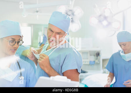 Surgeons with clipboard discussing paperwork in operating room Stock Photo