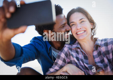 Smiling, enthusiastic multi-ethnic couple taking selfie with camera phone Stock Photo