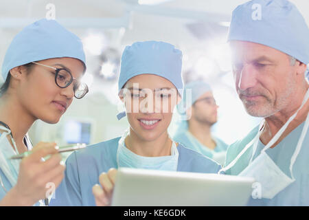 Surgeons using digital tablet in operating room Stock Photo