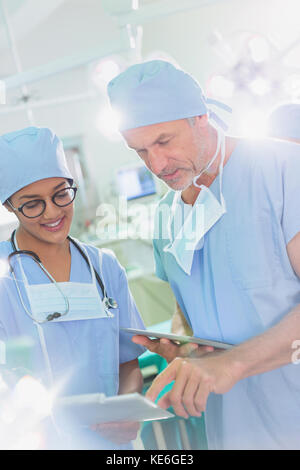 Surgeons with digital tablet and clipboard talking in operating room Stock Photo