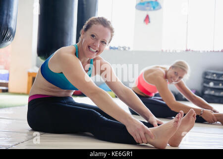 Smiling woman stretching legs in gym Stock Photo