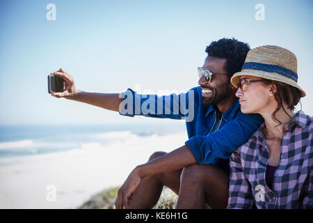 Multi-ethnic couple taking selfie on sunny summer beach Stock Photo