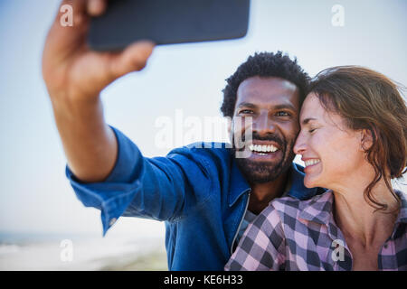 Affectionate, happy multi-ethnic couple taking selfie with camera phone Stock Photo