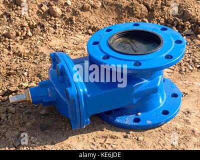 Detail of fittings, 150mm gate valves for drink water system. Repairing of piping in excavation pit. New blue painted gate valve on dry clay Stock Photo