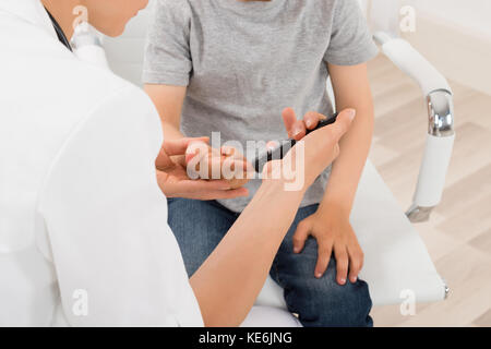 Close-up Of Doctor Measuring Blood Sugar Of Child Patient With Glucometer Stock Photo