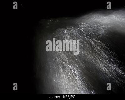 Shinning drops. Cascade of small weir on mountain stream, water is running over blocks and bubbles create milky smoky water level. Abstract, long expo Stock Photo