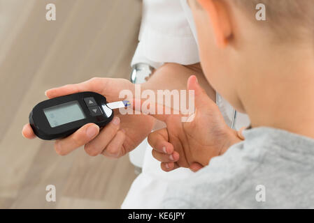 Close-up Of Doctor Measuring Blood Sugar Of Child Patient With Glucometer Stock Photo