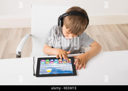 Boy Listening Music On Digital Tablet With Multicolored Apps On It Stock Photo
