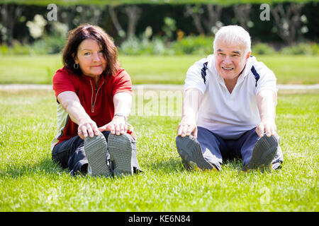 Elderly Senior Couple Doing Stretching Exercise In Park Stock Photo