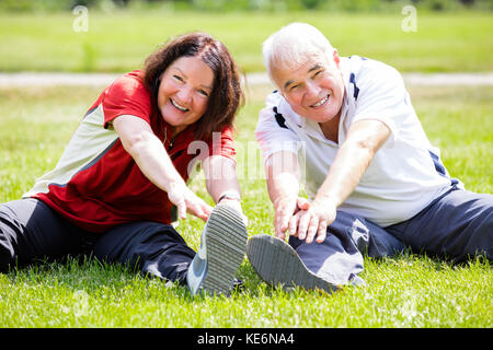 Smiling Senior Couple Doing Fitness Exercise In Park Stock Photo