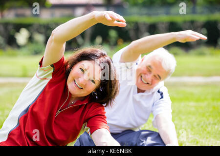 Happy Senior Couple Exercising In Park At Morning Stock Photo