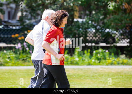 Smiling Senior Couple Running Together In Park Stock Photo