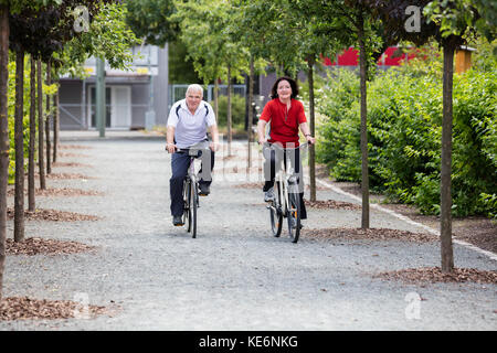 Happy Senior Couple Riding Bicycle In Park Stock Photo