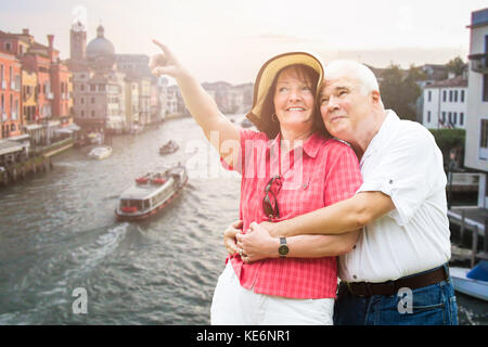 Smiling Senior Couple Pointing Finger In Front Of Grand Canal In Venice Stock Photo