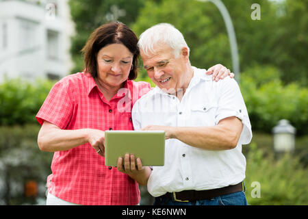 Happy Senior Couple Looking At Digital Tablet Stock Photo