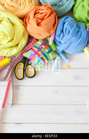 Colored fabric folded in the form of rose flowers. Scissors, tape measure, needle, needle bar, buttons. Stock Photo