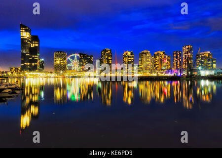 Still reflection of bright illuminated residential buildings towers Yarra river waterfront in Melbourne modern suburb Docklands at sunset. Stock Photo