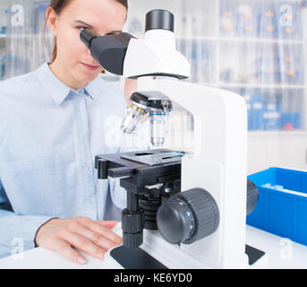 young woman scientific / female student researcher looking microscope  in a laboratory. Stock Photo