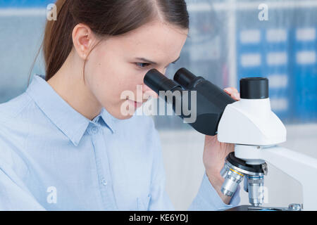 young woman scientific / female student researcher looking microscope  in a laboratory. Stock Photo