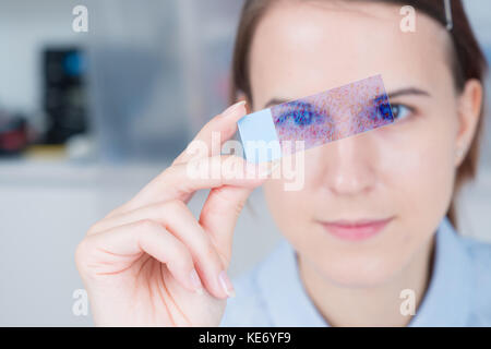 young woman scientific / female student researcher looking microscope slide  in a laboratory. Stock Photo