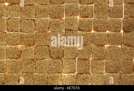 Background image of brown sugar cubes underlit to show gaps in the sugar Stock Photo