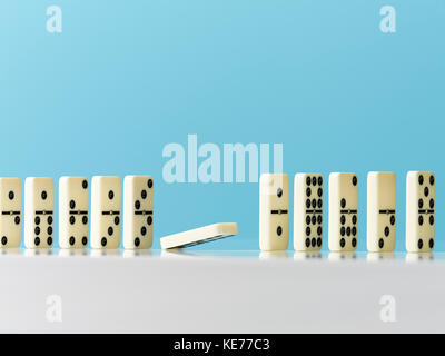 Domino falling in a row on blue background Stock Photo