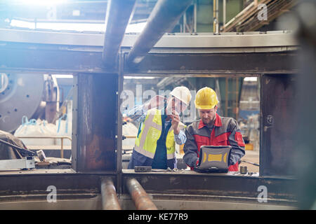 Male engineers with laptop examining parts in factory Stock Photo