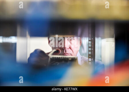 Focused male IT technician working in server room Stock Photo
