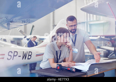 Airplane mechanics reviewing plans in hangar Stock Photo