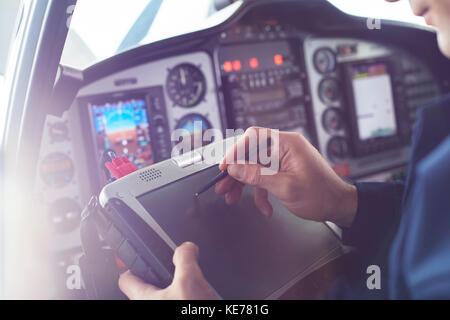Airplane pilot using stylus on digital tablet in cockpit Stock Photo
