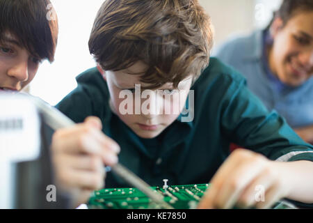 Focused boy student assembling electronics in classroom Stock Photo