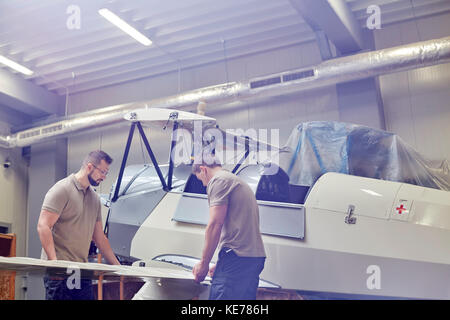 Male engineers assembling airplane in hangar Stock Photo