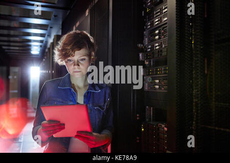 Focused female IT technician using digital tablet in server room Stock Photo