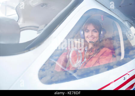 Portrait smiling female airplane pilot in cockpit Stock Photo