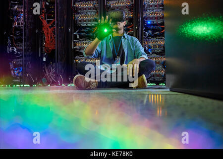 Male computer programmer using virtual reality simulator glasses in dark server room Stock Photo