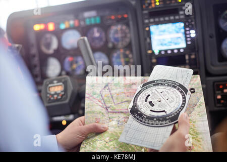 Pilot checking navigational map and compass instrument in airplane cockpit Stock Photo