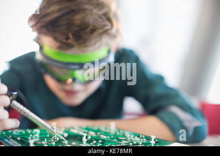 Focused boy student soldering circuit board in classroom Stock Photo