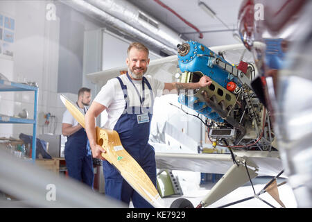 Portrait confident male engineer mechanic working on airplane in hangar Stock Photo