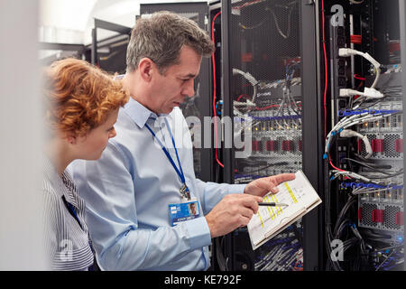IT technicians with clipboard examining panel in server room Stock Photo