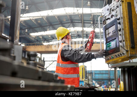 Male worker operating machinery at control panel in factory Stock Photo