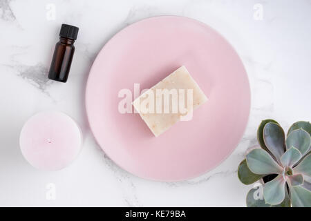 Styled lifestyle minimalist stock photo of an aerial selection of natural beauty products including an essential oil bottle, a pink candle, soap Stock Photo