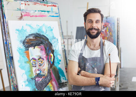 Portrait smiling, confident male artist painting in art studio Stock Photo