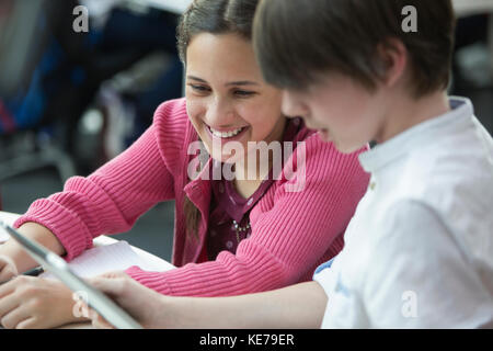 Smiling students using digital tablet in classroom Stock Photo