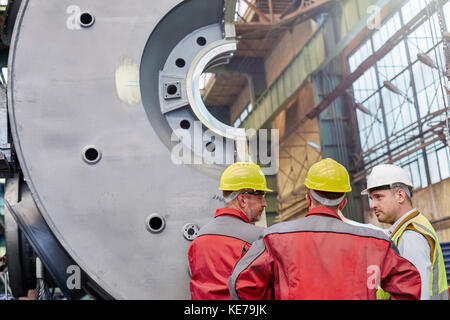 Male workers talking in steel factory Stock Photo