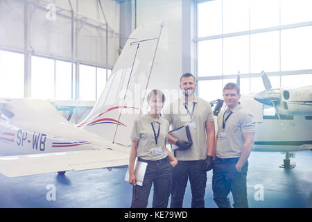 Portrait confident mechanic engineers standing in airplane hangar Stock Photo