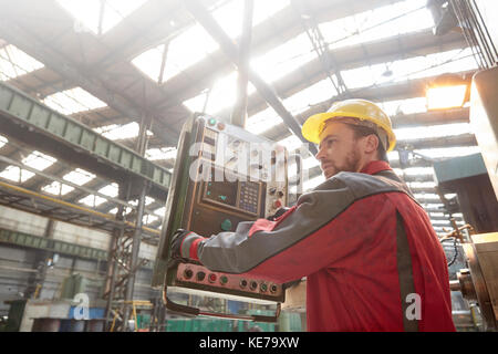 Male worker operating machinery at control panel in factory Stock Photo