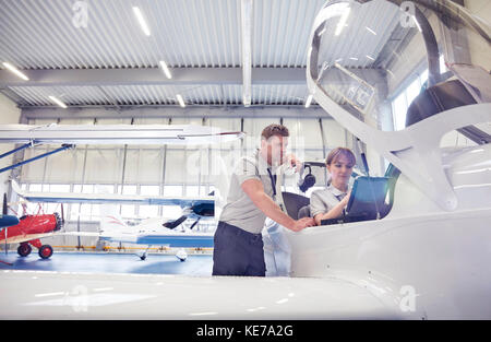 Mechanic engineers working in airplane cockpit in hangar Stock Photo