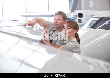 Mechanic engineers examining airplane wing in hangar Stock Photo