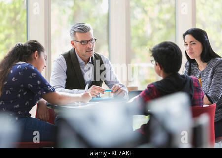 Teachers tutoring students at library table Stock Photo